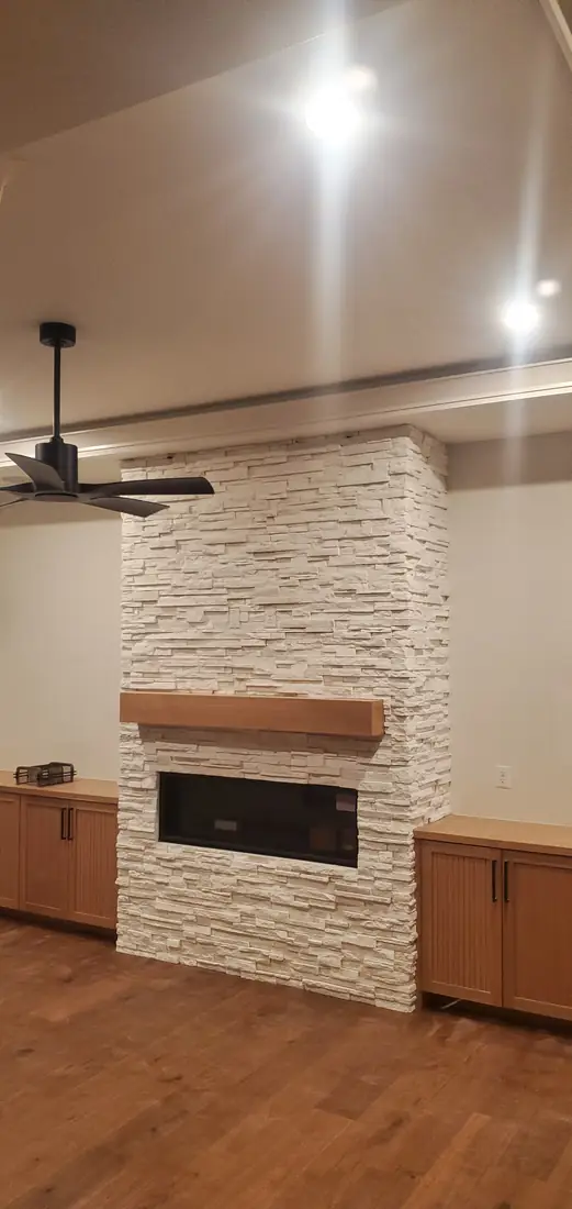 White textured stone veneer fireplace with mounted TV and sconce Oregon