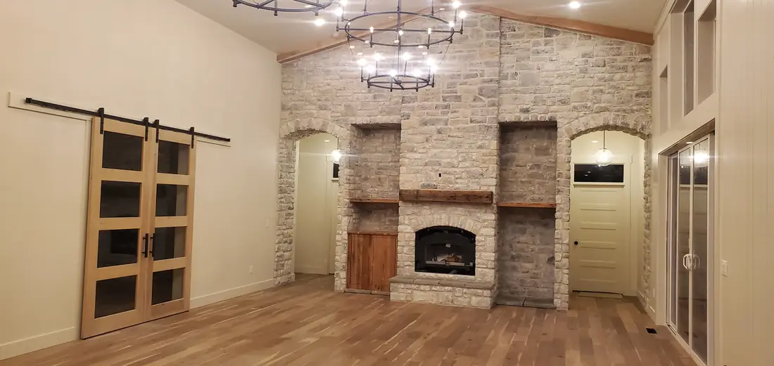 Brick veneer fireplace with barn doors and chandelier in living room Oregon