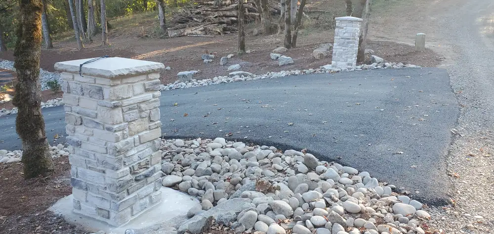 Stone veneer entry columns with river rock landscaping Oregon